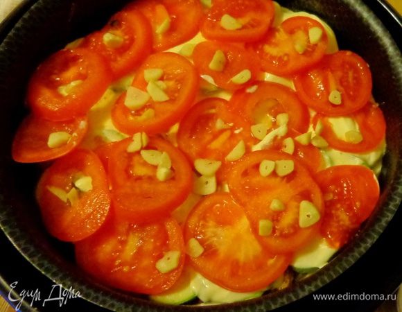 Сверху уложить нарезанные кружками помидоры и рубленый чеснок, посолить, поперчить.