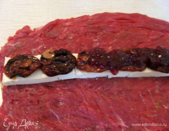 Отбитую вырезку нужно посолить и поперчить.
Ближе к одному краю я положила брынзу (обязательно твердую), порезанную крупными брусочками. Опять это мое изменение, можно ее порезать мелко и распределить по всей поверхности. В этом случае разрез будет выглядеть может  даже гармоничнее, но мне хотелось чтобы присутствовал крупный кусочек.
Поверх брынзы выложить вяленые помидоры, у меня они были уже в масле. Если помидоры сухие, то их нужно сначала размочить в оливковом масле.
Завершающий аккорд в нашей начинки - это клюква, протертая с сахаром или брусника, у меня клюква в этот раз.