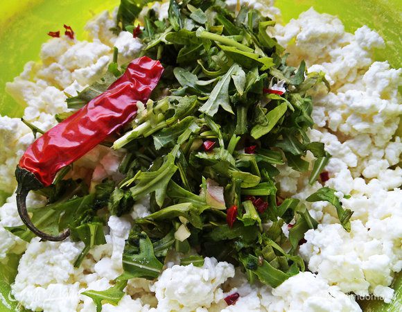 Высыпать рукколу с чесноком в творог. Отрезать от чили перца кусочек примерно в 1 см и покрошить кухонными ножницами.