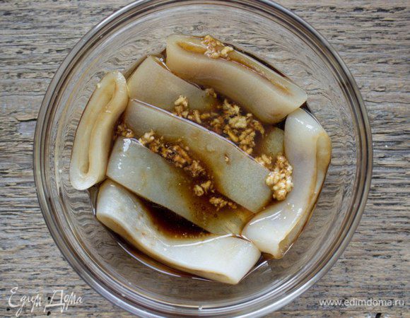 Положить кольца кальмара в глубокую чашку, выдавить через пресс чеснок, натереть на мелкой терке 1 см имбиря (можно взять 1/4 ч.л. имбирного порошка) и залить половиной объема маринада. Оставить на 20 минут