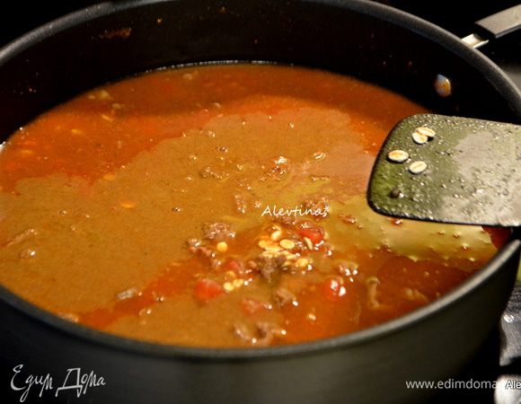 Добавить томатный соус, бульон, чили специю, тмин, перловку быстрого приготовления, томаты баночные с соком мелко порезанные. Закрыть крышкой и тушить 30 мин помешивая.