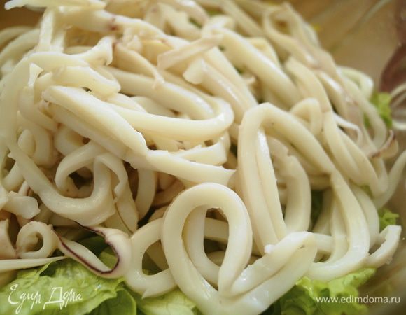 Салат порвать руками. Кальмары отварить в кипящей воде не более 2 минут, чтобы они не стали жесткими и нарезать тонкими кольцами. Добавить в салатник вместе с листовым салатом.