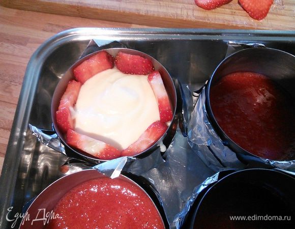 Теперь осталось собрать десерт: клубнику, отложенную в сторону, нарежьте пластинками (по 4-5 с одной ягоды). Достаньте из морозилки заготовки и наполните формочки на половину кремом, выложите бортики клубничными пластинками. В креме клубника хорошо держится, несмотря на это Вам понадобится некая ловкость рук и ювелирная точность, т. к. от этого зависит в дальнейшем внешний вид вашего десерта.