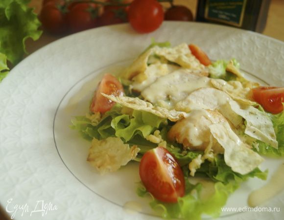 На тарелку, в которой будем подавать салат, выложить листья салата, порванные на крупные части. Затем поместить нарезанное куриное филе, посыпать тертым сыром, полить соусом и выложить помидорки. Чипсы из лаваша выложить на салат непосредственно перед подачей на самый верх, иначе они размокнут.