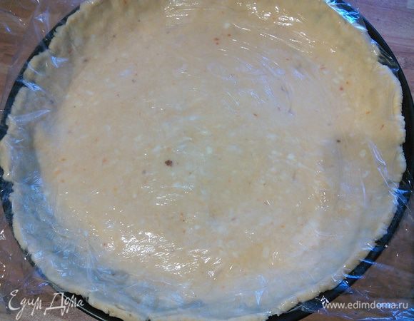 Смажьте форму для киша маслом и распределите тесто по форме, образуя бортики. Я распределяю его прямо под плёнкой, нажимая руками. Не убирая плёнки поставьте заготовку в холодильник. 