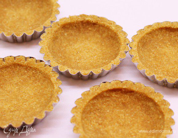 Добавьте растопленное сливочное масло и сахар. Перемешайте до однородности массы. Заполните и распределите массу равномерно, по форме тарталеток.
Выпекайте 4-5 минут при 190С или до золотистого цвета.
Остудите основу и достаньте из формы.