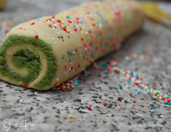  Раскатать обе части теста по отдельности между двумя листами бумаги для выпечки.  Если тесто будет слишком мягким - уберите его на несколько минут  морозилку. 

Далее поверх светлой части теста выложить зеленое и скрутить плотным рулетом.  Обвалять рулет в кондитерской посыпке, прикрыть пищевой пленкой и убрать в холодильник на 1 час.