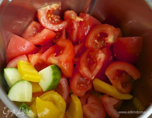 Помидоры ошпарить кипятком и очистить от кожуры и семян. Нарезать кубиками. Выложить в чашу блендера, добавить оставшийся сладкий перец и огурец. К овощам добавить оливковое масло, свежевыжатый сок апельсина. Включить блендер и измельчить овощи.