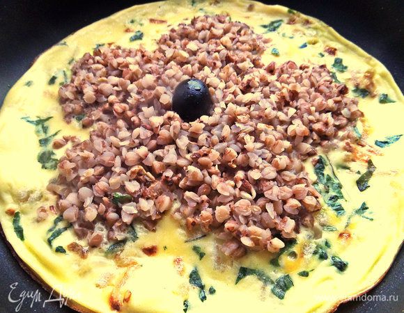 Снимаем омлет с огня. Переносим на блюдо и начинаем украшать. В центр вдавим маслинку.