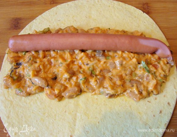 Выложить на лепешку 1/6 часть фасолевой массы сверху положить сосиску