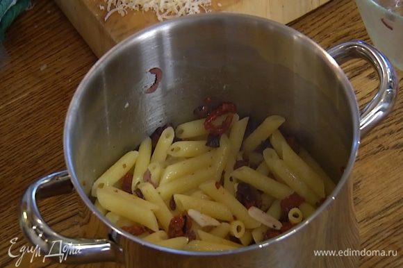 В горячие макароны выложить заправку, перемешать, затем добавить большую часть моцареллы и сыра.