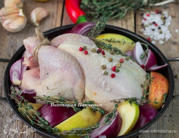 Яблоки, красный лук и вторую половину лимона нарезать дольками. Выложить в порционные сковородки, немного посолить, сверху выложить цыплят. Посыпать целым розовым перцем, выложить веточки тимьяна. В одну порцию я добавила пропущенный через пресс чеснок, в другую положила 1/2 головки чеснока, разрезанной поперек зубков.