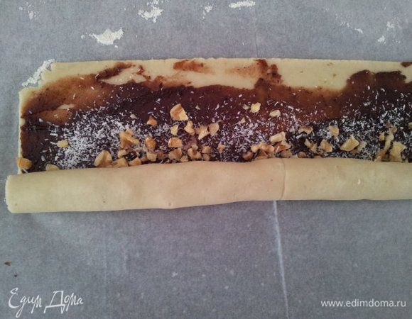 Тесто сворачиваем при помощи бумаги, на которой оно лежит, помогаем руками, немного подтягиваем.