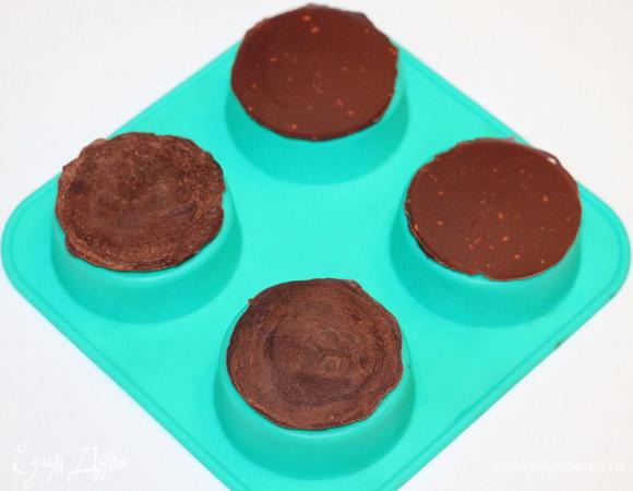 Берем силиконовые формочки, переворачиваем их как на фото и смазываем верх (чайной ложкой) растопленным шоколадом. У меня получилось 12 кружочков (Ф ~6 см), т. е. на четыре больших пирожных по три кружка. Вместо силиконовых формочек, можно взять силиконовый коврик или пергаментную бумагу (смазать маслом). Кружочки отправляем в холодильник до застывания шоколада.
Застывшие кружочки слегка поддеваем ножиком и они легко снимаются с формочки.