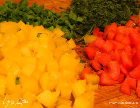 Тем временем подготовить овощи. Перец нарезать кубиками. Зелень укропа и чеснока помыть и нарезать мелко.