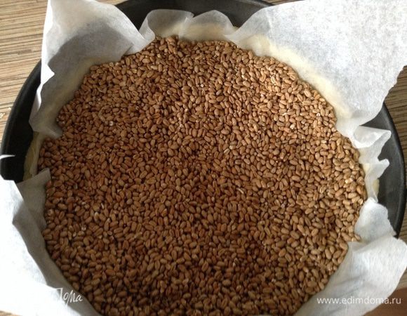 Достаем форму из морозилки, кладем пергамент или фольгу, засыпаем груз и отправляем в духовку при 200С на 10 минут.