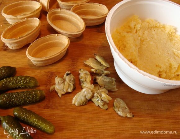 Сыр (типа гауды) натереть на мелкой терке. Смешать с соусом. У меня был горчичный соус, можно использовать любой по вкусу. Наполнить сыром тарталетки. Украсить огурчиком и ракушками.