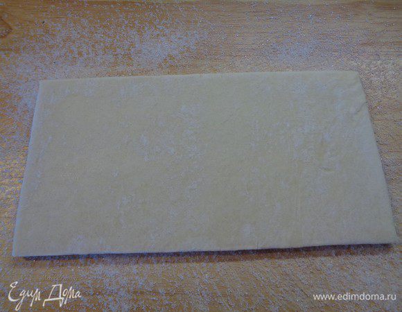 Положить пласт слоеного теста поверх сахара и тоже присыпать его сахаром.