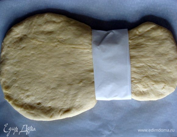 Тесто раскатать так, чтобы один край был шире другого. Свернуть пергамент в 3 слоя и перетянуть тесто чуть ниже середины. Это нужно для формирования основы снопа. Накрыть тесто пленкой, оставить еще на 1 час для подъема.