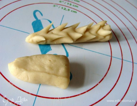 За это время можно приготовить из белкового теста элементы для колосьев.
От теста отрезать кусочек, раскатать, разрезать пополам, чтобы получились конусообразные половинки. Маленькими маникюрными ножничками сделать надрезы. Таких колосков у меня получилось около 30 шт.