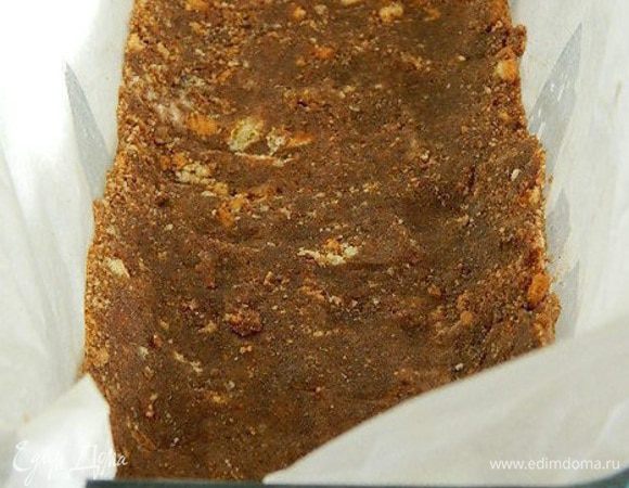 Печенье измельчить в крошку. Добавить мягкое сливочное масло, перемешать. Форму застелить пекарской бумагой и выложить печенье. Утрамбовать и убрать в холодильник.