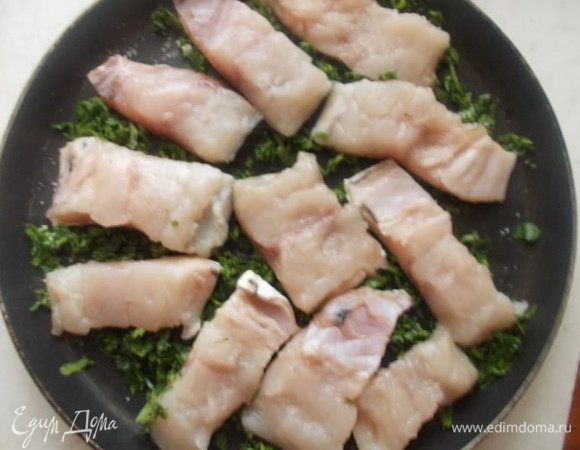 Укладываем на небольшую сковородку зелень равномерно, а сверху рыбку, кожей вниз, наливаем немножко водички, чтобы она только покрывала зелень, буквально несколько ложек. Солим и отправляем на средний огонь.