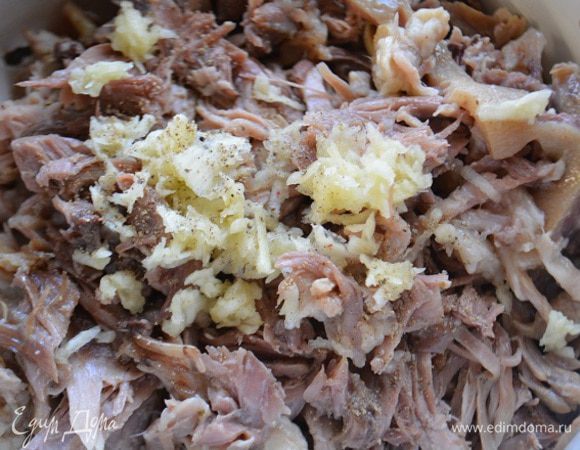 Мясо разобрать на волокна и добавить чеснок через пресс и свежемолотый черный перец, перемешать.