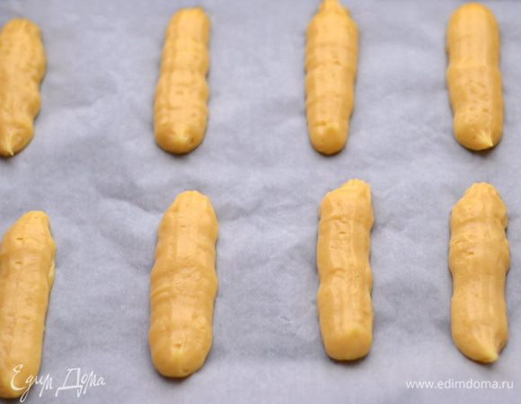 Заполняем заварным кремом кулинарный шприц или кулинарный мешок и выдавливаем небольшие ровные палочки на противень, застеленный пергаментом.
