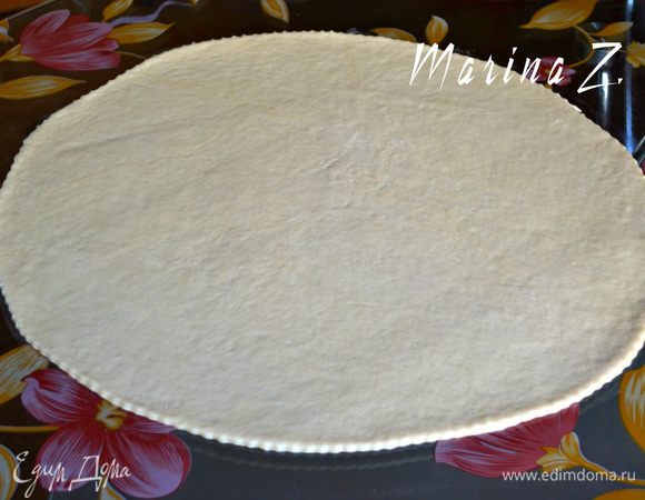  Тесто вынуть из пакета, слегка помять на столе. Разделить его на 4 части (хватит на 2-3 больших пирога). Одну часть раскатать в овал толщиной примерно в 7 мм.