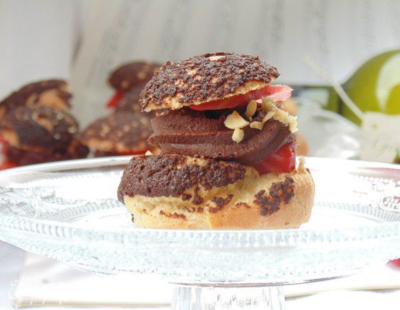 Крем: сливки довести до кипения, залить поломанный на дольки шоколад, хорошо размешать, остудить в холодильнике, взбить миксером.
У пирожных срезать верхнюю часть (1/3), наполнить кремом, украсить дольками клубники и дробленным фундуком.
Приятного аппетита!