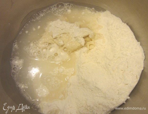 В отдельную миску насыпать муку, добавить опару, воду и все перемешать.