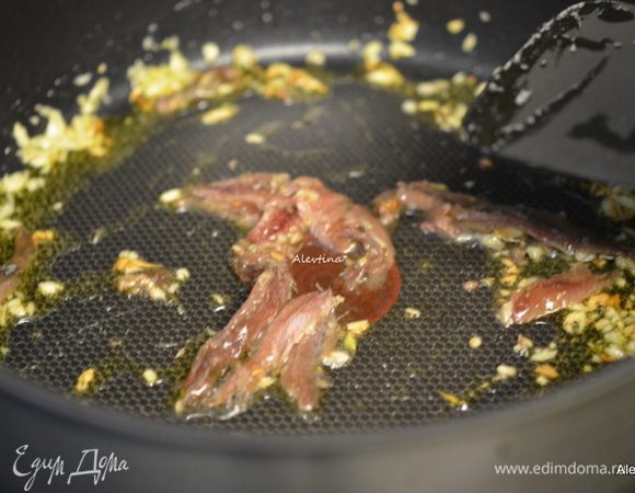 Оливковое масло вылить на сковороду, добавить чеснок мелко порубленный. Затем баночку 56 г  очищенное филе анчоусов, все помешать. Как только масло нагреется, филе анчоусов разойдется по кусочкам. 