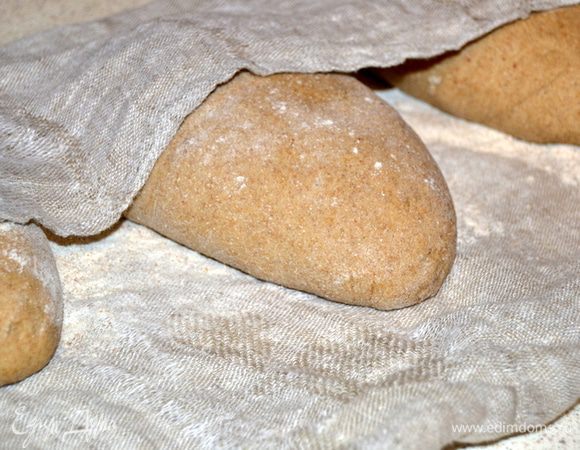 По истечении времени, выкладываем тесто на стол, делим на три части, формируем шары и оставляем под полотенцем на 5 минут. Тем временем противень застелить полотенцем и посыпать мукой. Из теста формируем батоны и укладываем на полотенце. Оставляем между ними место. Накрываем вторым полотенцем и оставляем на 1,5 часа. Затем аккуратно перекладываем на противень.