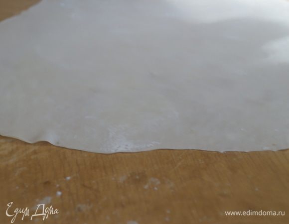 Раскатываем тесто в достаточно тонкий пласт. Чтобы оно не липло к скалке присыпаем немного его крахмалом и раскатываем в разные стороны тонко-тонко.