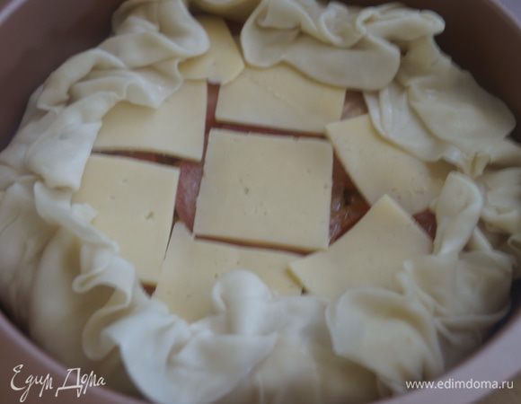 Оставшийся помидор режем тонкими кружочками и выкладываем поверх начинки. Сыр режем тонкими пластинами и также выкладываем на начинку. Собираем свисающие края теста, формируя бортик.