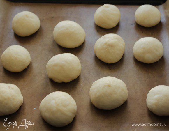На подпыленный мукой стол выложить тесто и разделить его на 12 частей. Сформировать шарики, выложить их на застеленный пергаментом противень, накрыть пленкой и оставить тесто на 30-45 минут до увеличения вдвое.