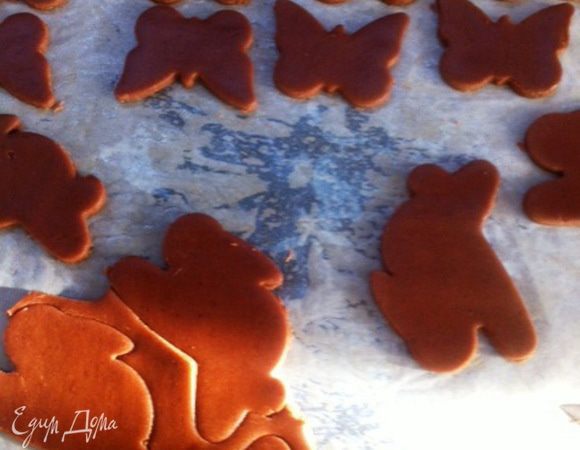 Вырезаем из теста фигурки, используя формочки. Перекладываем лист бумаги с фигурками на противень.