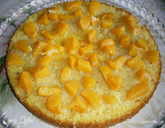 Приступаем к сборке. На пропитанный бисквитный пласт выкладываем половину персиков.