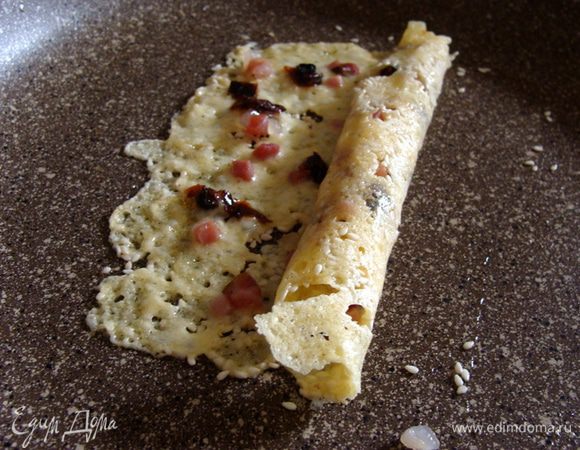 Распределить начинку. Подождать пол минутки буквально, пока сыр подстынет и аккуратно свернуть трубочку, используя лопатку.
