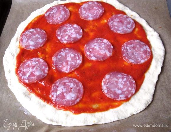 Начинка. Шампиньоны порезать пластинками, колбасу, горький перец (зеленый или красный) тонкими колечками, зерна удалить, пармезан натереть на крупной терке. Тесто раскатать в круг, обмазать остывшим томатным соусом, немного отступив от края, выложить колбасу.