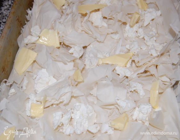 Оставшиеся листы теста можно разрезать пополам или как угодно, скомкать как лист бумаги и раскидать как попало по форме. Накрошить брынзу и сливочное масло.