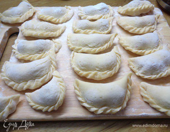 Таким образом слепить все вареники и уложить их на хорошо посыпанный мукой поднос. Вишню доставать из морозильника постепенно, по мере лепки вареников. Для того, чтобы она не пустила сок.