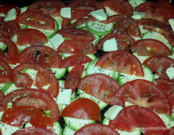 На смазанный оливковым маслом противень выкладываем кабачки, сверху помидоры, немного солим, перчим и посыпаем сушеным базиликом. 

Раскладываем равномерно кусочки сливочного масла.