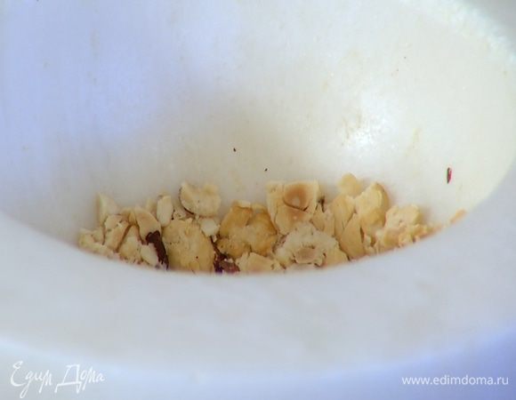 Половину орехов измельчить в ступке в крупную крошку, добавить во взбитые сливки и перемешать.