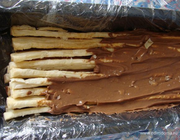 Потом слоями выкладывать полоски теста и обильно смазывать кремом.
Завернуть пленку, придать полену круглую форму и положить в холодильник на ночь.
Возможно форму ровного полена получится придать не сразу. Нужно немного полежать заготовке уже в завернутом виде и дать крему впитаться. Потом форма придается легко.