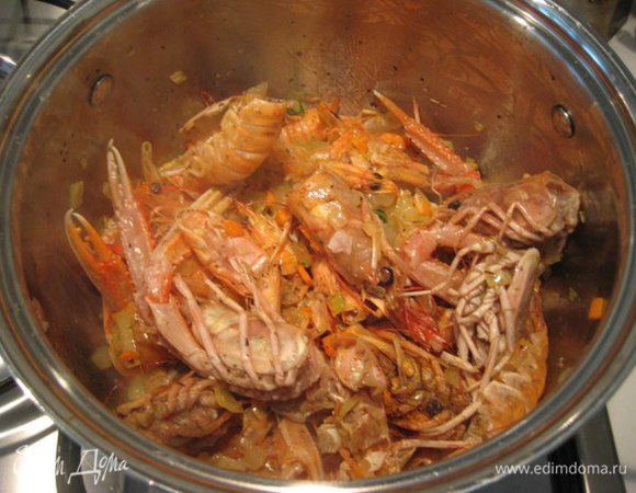 Добавить головы и панцири лангустинов (креветок), готовить 3-4 минуты помешивая. Влить вино, увеличить огонь, дать алкоголю выпариться. Влить воду, довести до кипения, уменьшить огонь и готовить 20-25 минут.