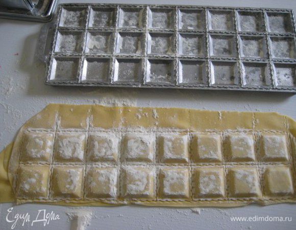 Наполните лунки начинкой, смажьте слегка тесто вокруг начинки водой и накройте вторым пластом теста. Покатать сверху скалкой, чтобы сформировались равиоли. 