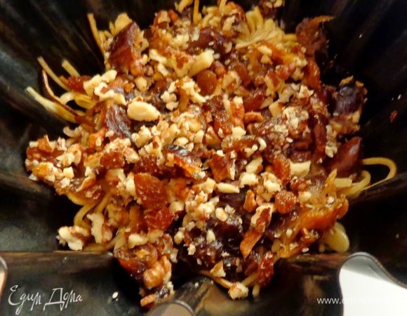 Готовое тесто измельчить, залить растопленным сливочным маслом, дать ему хорошенько пропитаться. Половину теста положить в неразъемную смазанную форму и немного утрамбовать.Сверху положить начинку: изюм и измельченные орехи и финики. Можно добавить лимонную цедру.