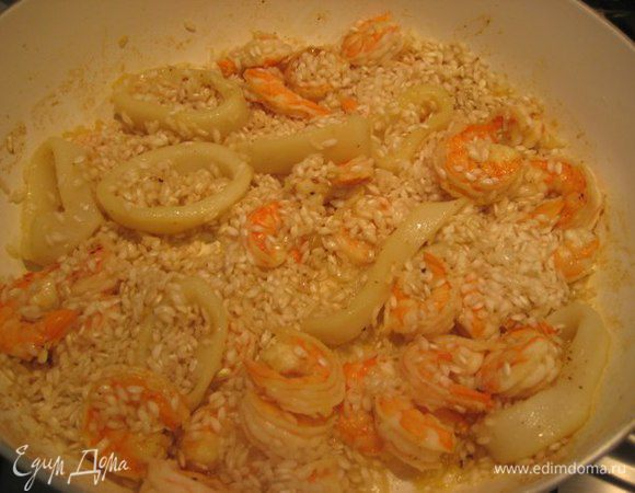 Когда морепродукты дадут сок, всыпать рис. Рис не промывать. Готовить, помешивая, пару минут. Увеличить огонь, влить вино, дать алкоголю выпариться.