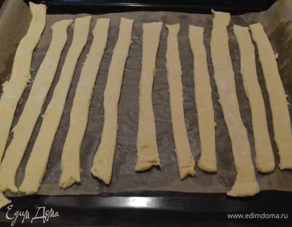 Слоеное тесто нарезать пластинками (~1см шириной), выложить на противень 